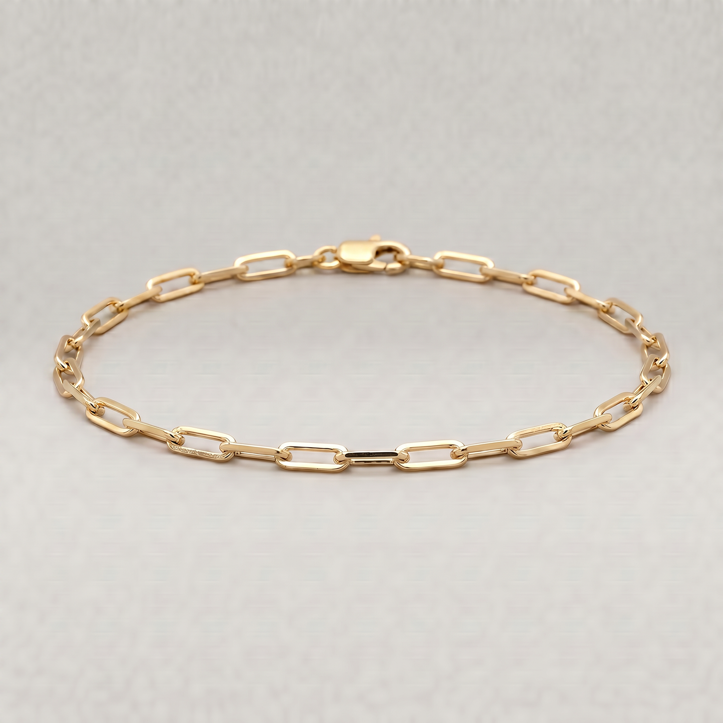 Gold plated sterling silver paperclip chain bracelet, 2.7mm, on a plain background.