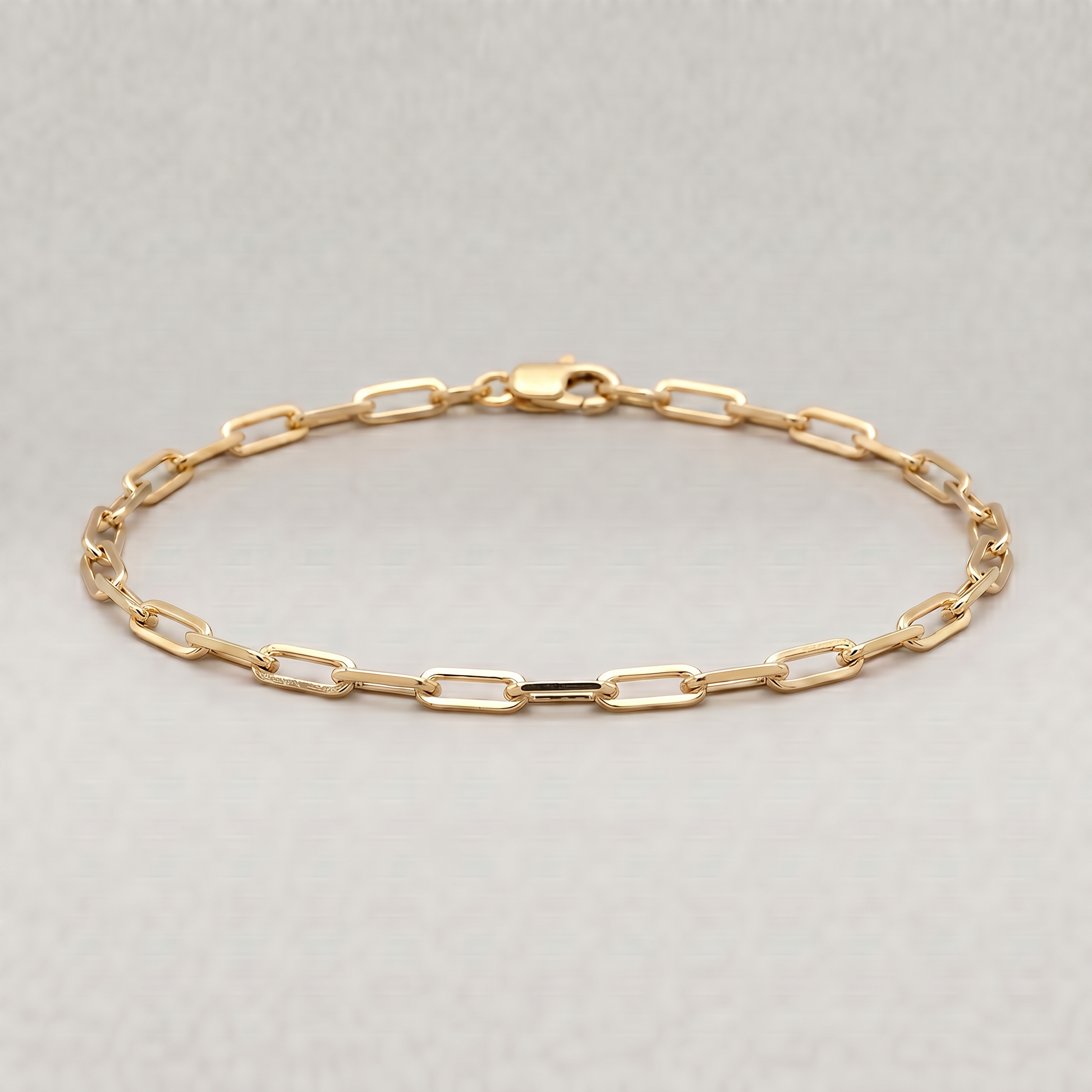 Gold plated sterling silver paperclip chain bracelet, 2.7mm, on a plain background.