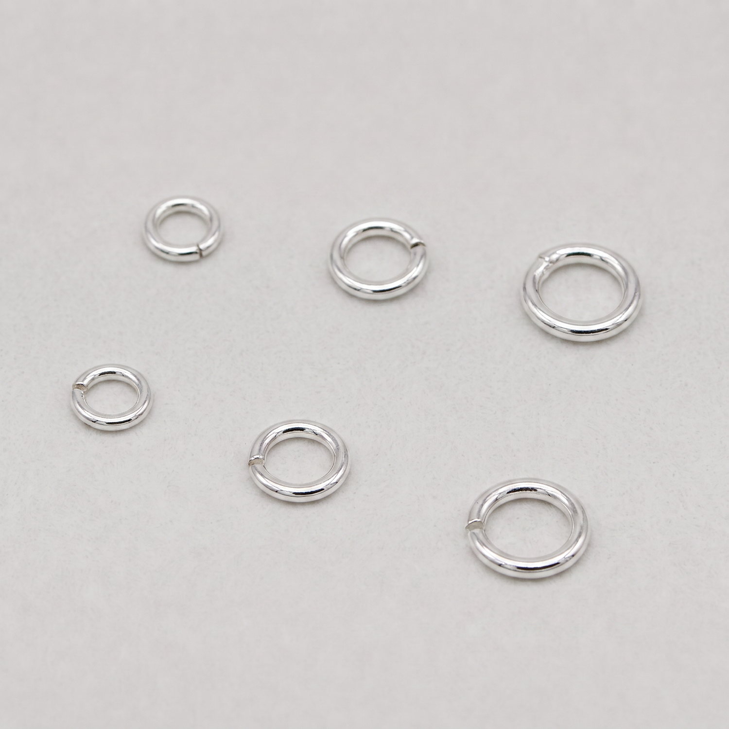 925 sterling silver open and closed jump rings, 4mm to 6mm, for jewellery making, on a plain background.